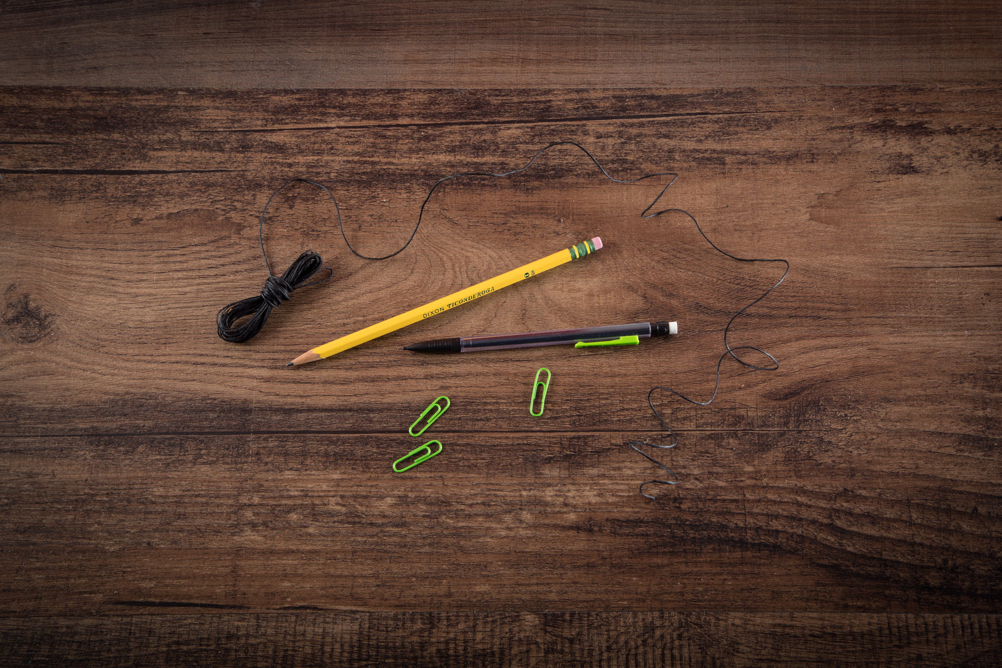 String, pencils, and paperclips on a wooden table.